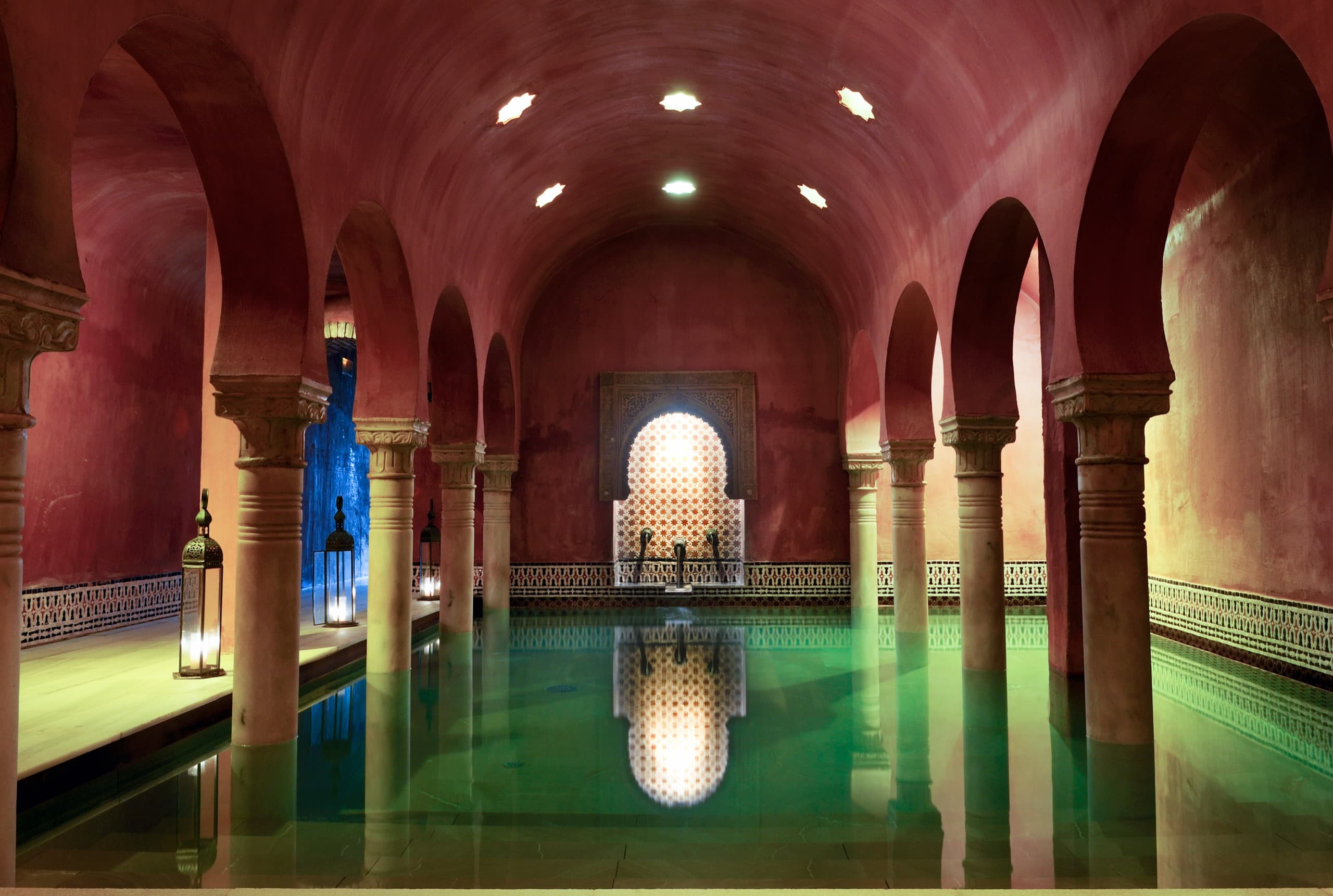 Bassin sous une enfilade d’arcs outrepassés en fer à cheval, colonnes de pierre et lanternes