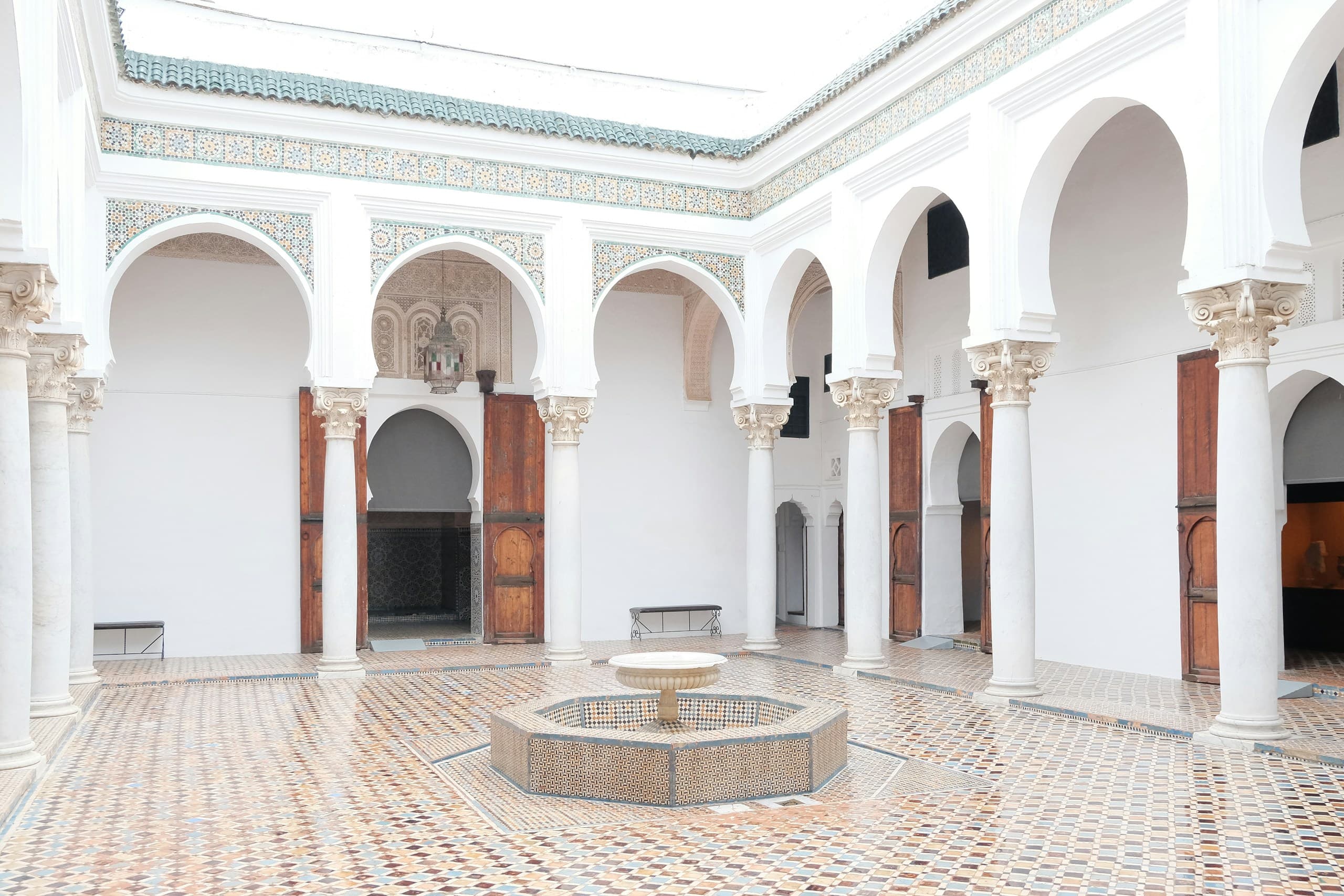 Cour de riad blanche à arcades sur colonnes, fontaine ronde au centre