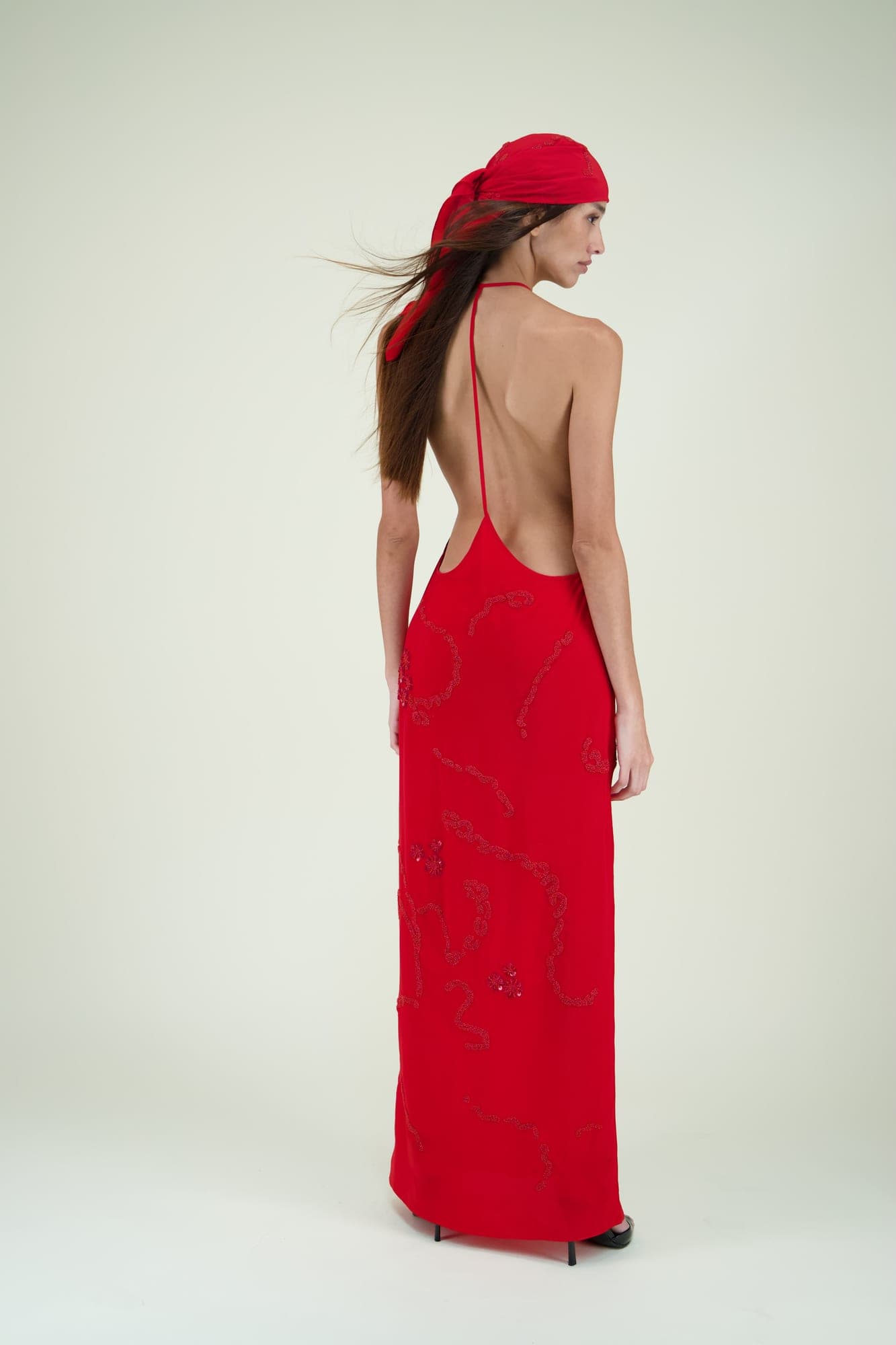 Mannequin de dos en robe longue rouge à dos nu et foulard assorti, sur fond clair